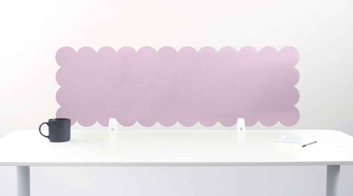 Pink scalloped headboard on a white wall with a white table and black mug in the foreground.