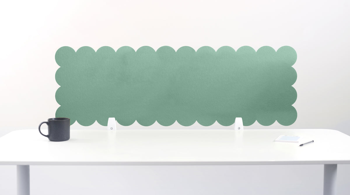 Green scalloped headboard against a white wall with a white desk and black mug.