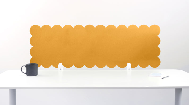 Yellow scalloped office partition against a white wall with a desk and mug in the foreground.