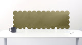 Scalloped green panel on a white wall above a white table with a black mug.