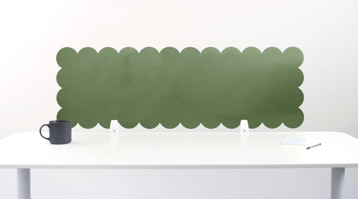 Green scalloped headboard against a white wall with a white table and black mug.