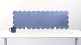 Scallop-shaped blue screen partition behind a white desk with a black mug on a white background