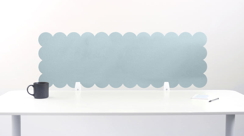 Scallop-shaped light blue screen on a white desk with a black mug.