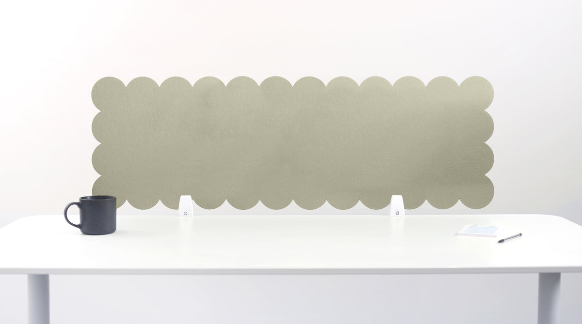 Scalloped green headboard on a white wall above a white bed frame with a black mug on a white surface.