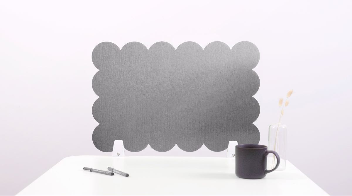 Black cloud-shaped screen on a white surface with a pen and mug.