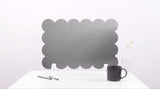Black cloud-shaped screen on a white surface with a pen and mug.