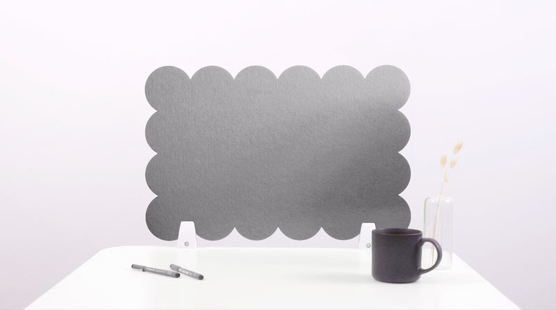 Black cloud-shaped screen on a white surface with a pen and mug.