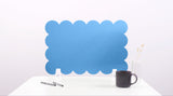 Blue scalloped screen on a white surface with a black mug and pen.