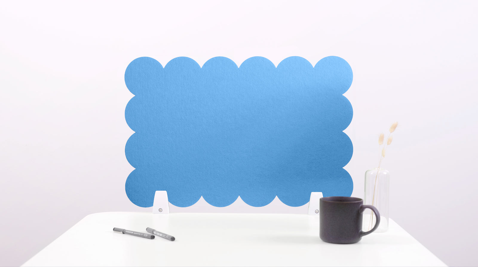 Blue scalloped screen on a white surface with a black mug and pen.