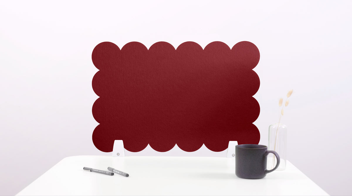 Red scalloped screen on a white surface with a black mug and pen.