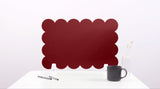 Red scalloped screen on a white surface with a black mug and pen.
