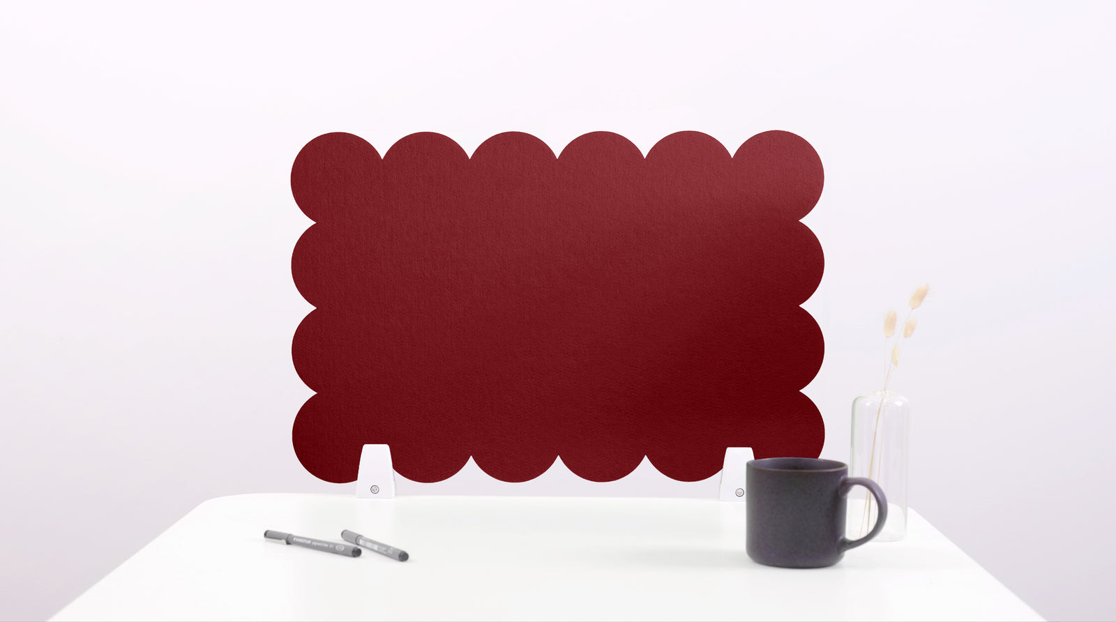 Red scalloped screen on a white surface with a black mug and pen.