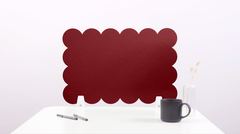 Red scalloped screen on a white surface with a black mug and pen.