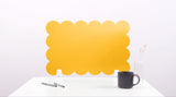 Yellow scalloped screen on a white surface with a black mug and pen holder.