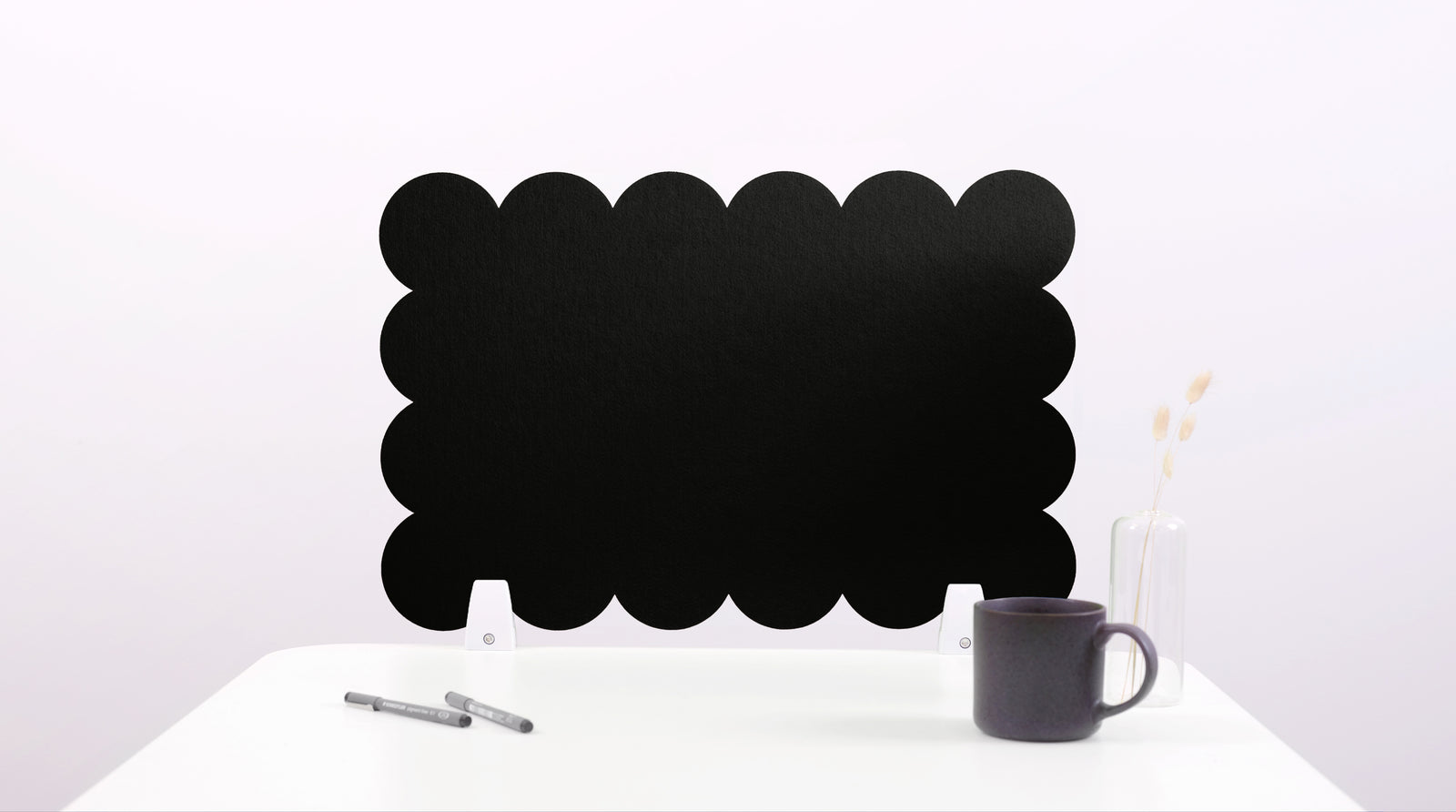 Black cloud-shaped chalkboard on a white surface with a pen and mug.