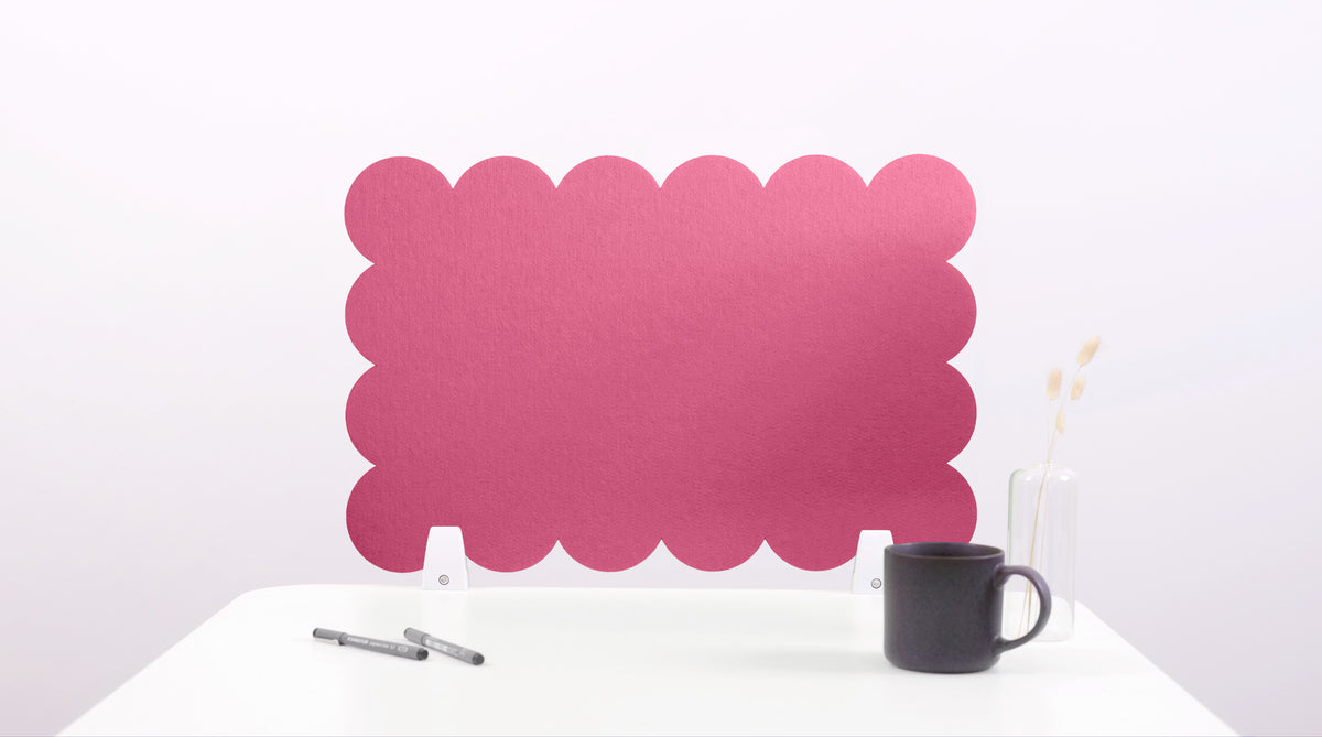 Pink scalloped screen on a white surface with a black mug and pen.