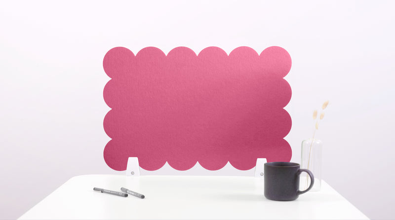 Pink scalloped screen on a white surface with a black mug and pen.