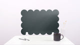 Green scalloped screen on a white surface with a black mug and pen.