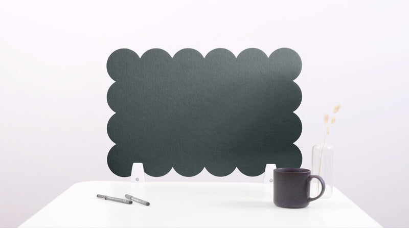 Green scalloped screen on a white surface with a black mug and pen.