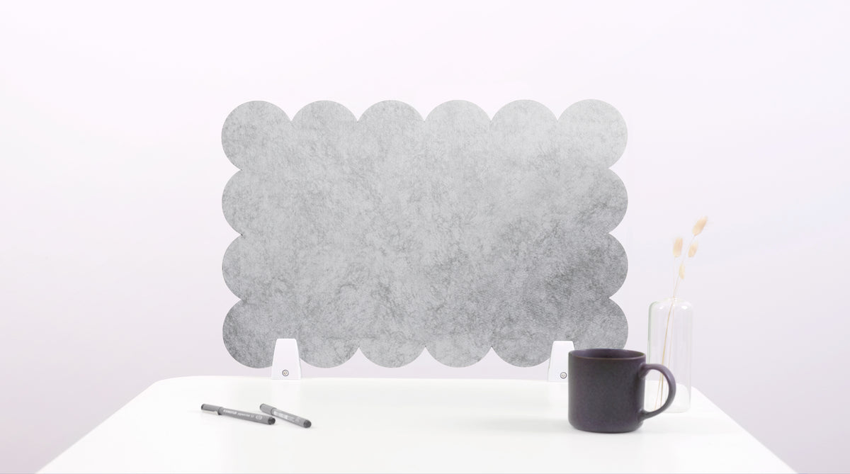 Gray bubble-shaped felt screen on a white surface with a black mug and pen.