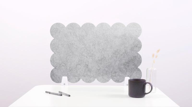 Gray bubble-shaped felt screen on a white surface with a black mug and pen.
