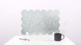Decorative wall panel with scalloped edge on a white surface with a black mug and pen.