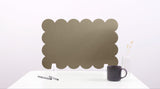 Green scalloped screen on a white surface with a black mug and pen.