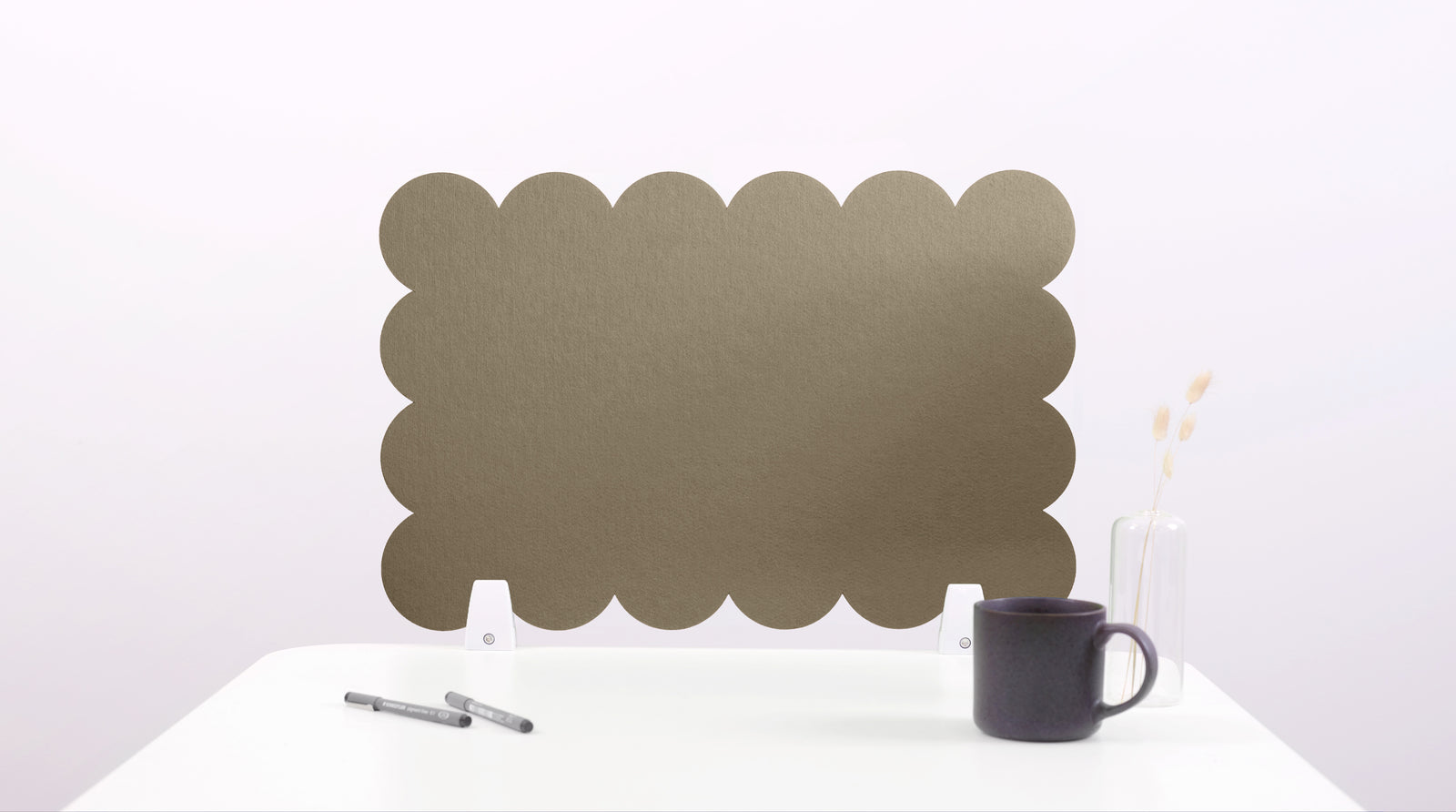 Green scalloped screen on a white surface with a black mug and pen.