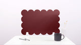 Red scalloped screen on a white surface with a black mug and pen.