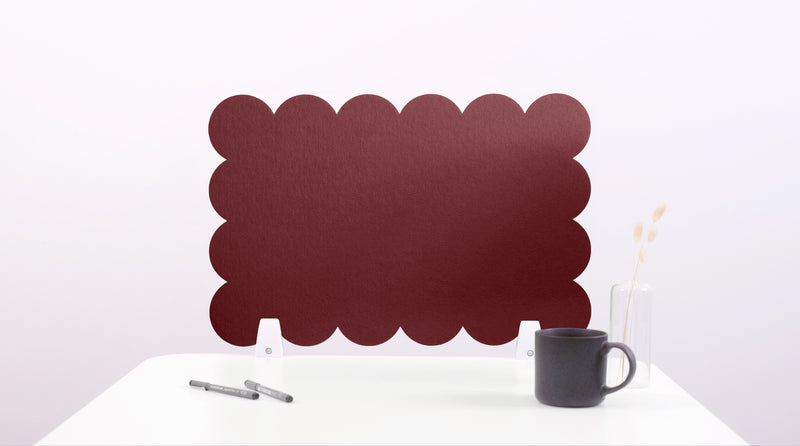 Red scalloped screen on a white surface with a black mug and pen.