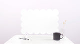 Black mug on a white surface with a white cloud-like object in the background