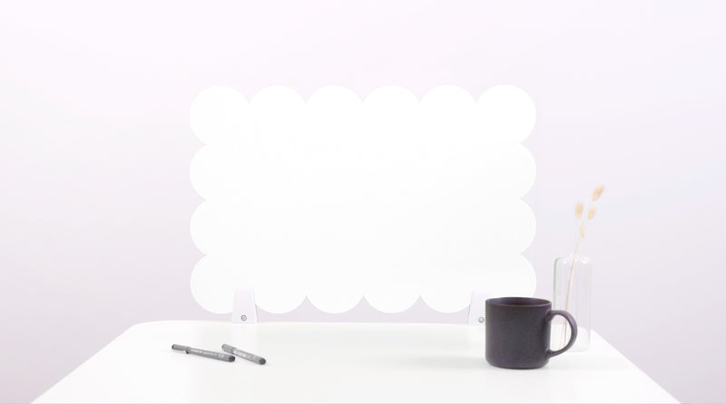 Black mug on a white surface with a white cloud-like object in the background