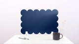 Navy blue scalloped edge screen on a white surface with a pen and mug.