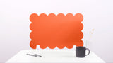Orange scalloped headboard on a white background with a black mug and pen.