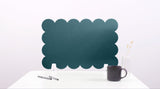 Navy blue scalloped edge screen on a white surface with a pen and mug.