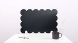 Black cloud-shaped chalkboard on a white surface with a pen and mug.