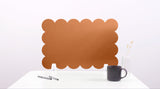 Brown scalloped desk screen on a white surface with a black mug and pen.