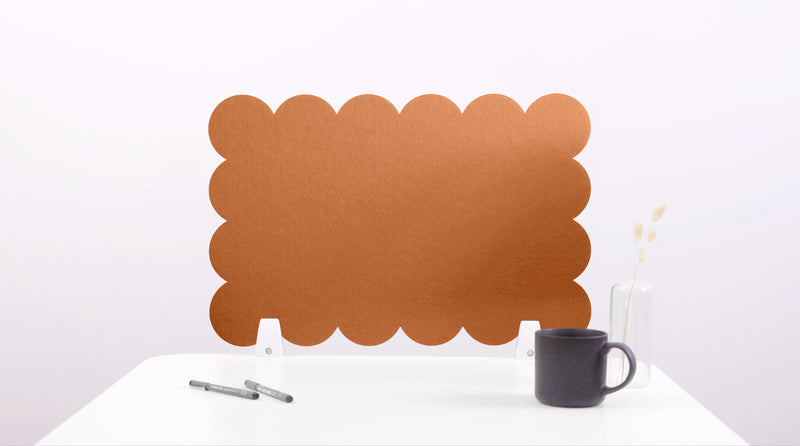 Brown scalloped desk screen on a white surface with a black mug and pen.