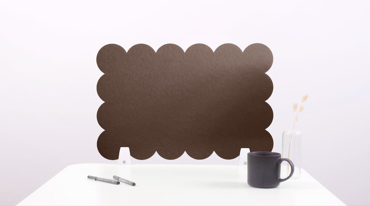 Black scalloped screen on a white surface with a mug and pen.