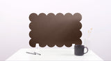 Black scalloped screen on a white surface with a mug and pen.