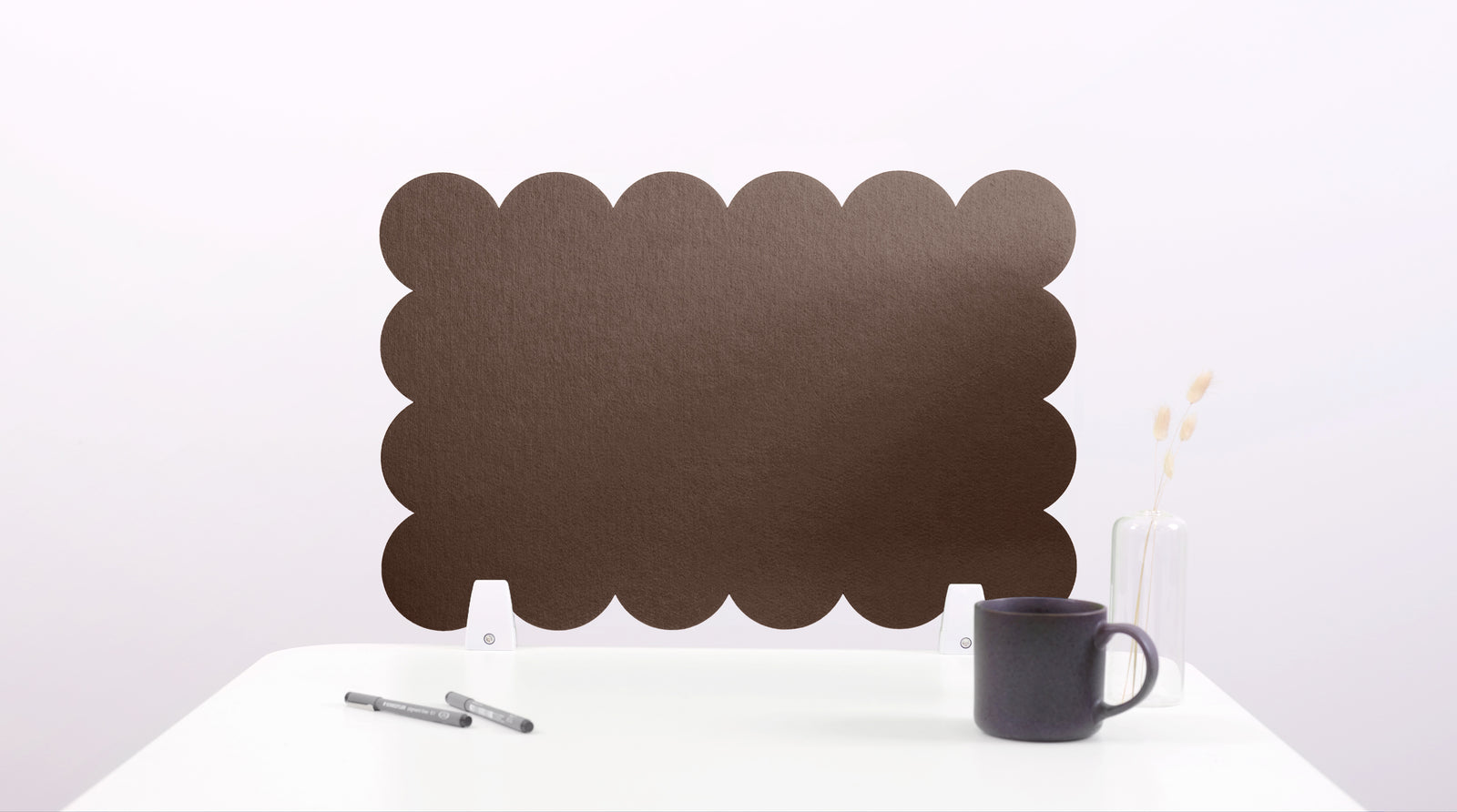 Black scalloped screen on a white surface with a mug and pen.