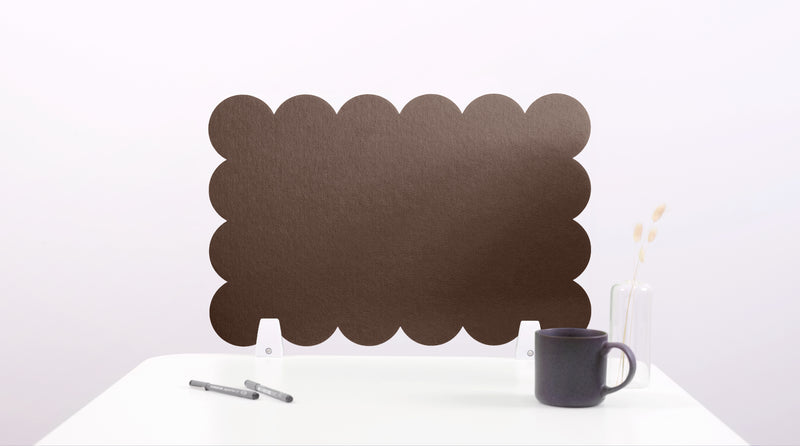 Black scalloped screen on a white surface with a mug and pen.