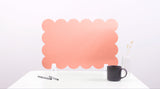 Pink cloud-shaped screen on a white surface with a black mug and pen.