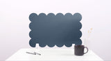 Black cloud-shaped desk divider on a white surface with a mug and pen.