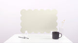 White cloud-shaped placemat on a white surface with a black mug and pen.