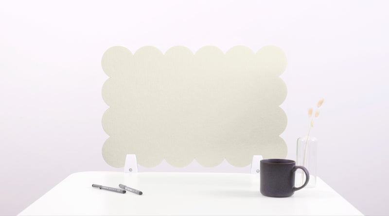 White cloud-shaped placemat on a white surface with a black mug and pen.