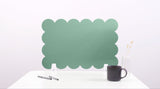 Green scalloped headboard on a white background with a black mug and pen.