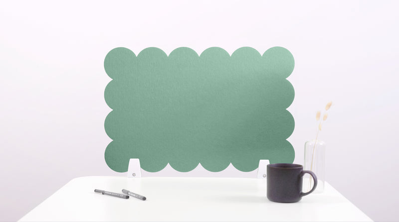 Green scalloped headboard on a white background with a black mug and pen.