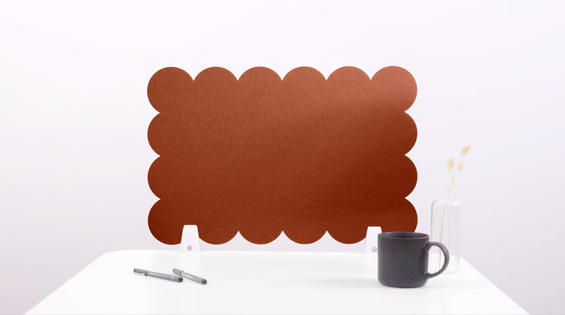 Brown scalloped placemat on a white surface with a mug and pen.