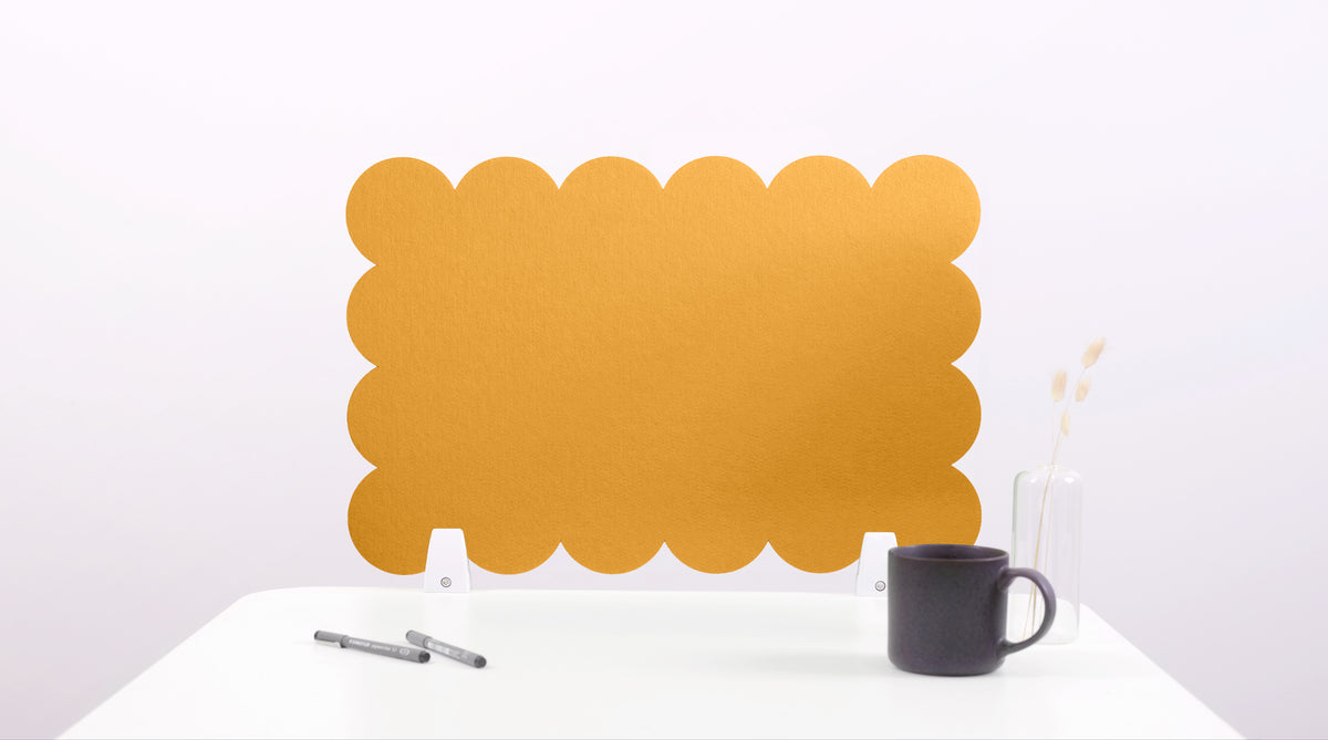 Yellow scalloped placemat on a white surface with a black mug and pen.